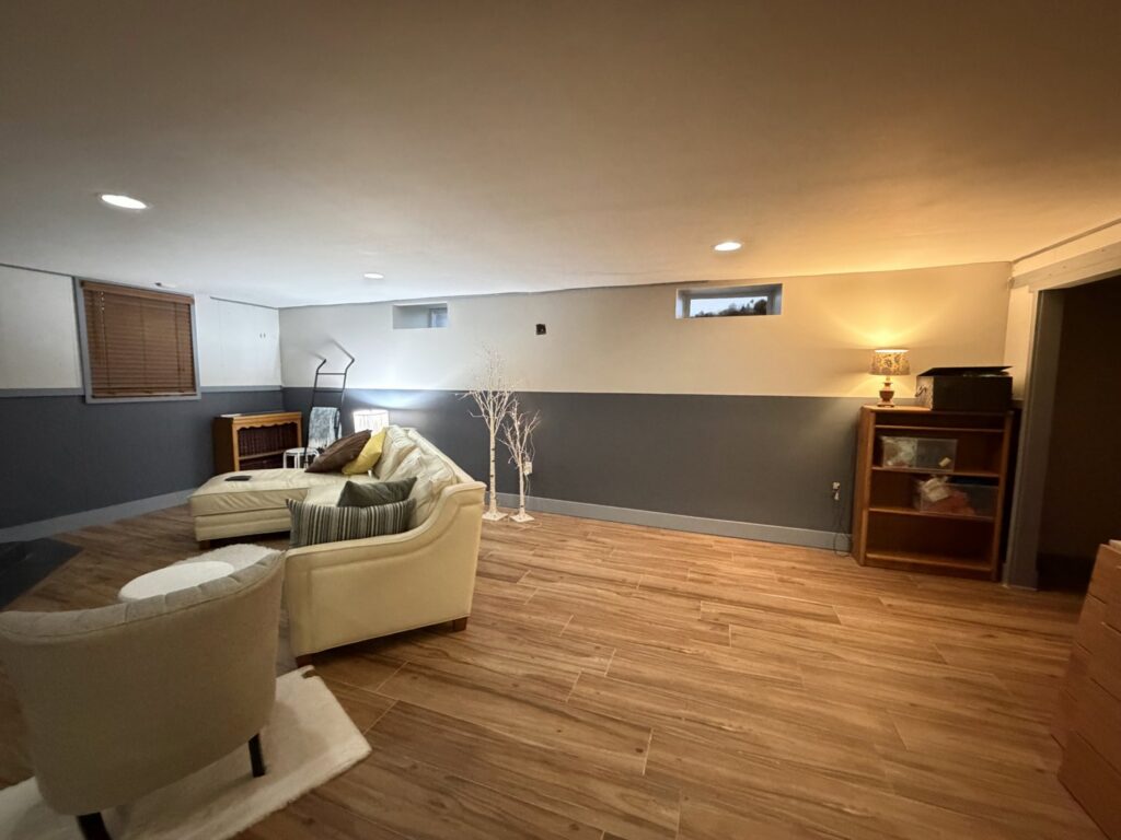 A newly finished basement living area with modern flooring and two-tone painted walls, completed by OG Renovations in Huntington, WV.