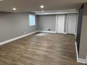 A newly finished basement living area with modern flooring and recessed lighting by Silhouette Builders, Inc. in Yorkville, IL