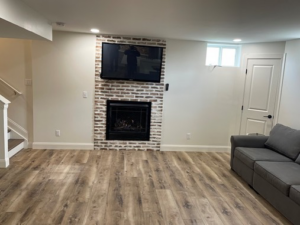 A newly finished basement living area with a fireplace and mounted TV by Smith Construction Services in Cincinnati, OH