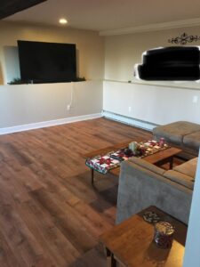 A newly finished basement living area featuring new flooring and fresh paint, completed by Granite State Handyman & Home Repair in Derry, NH.