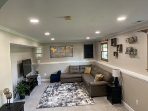 A completed finished basement living room with recessed lighting and new flooring by Garrett Group Construction in Philadelphia, PA.