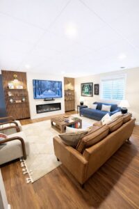 A finished basement living room with an electric fireplace and custom shelving by Pluff Contractors LLC in Lancaster, PA.