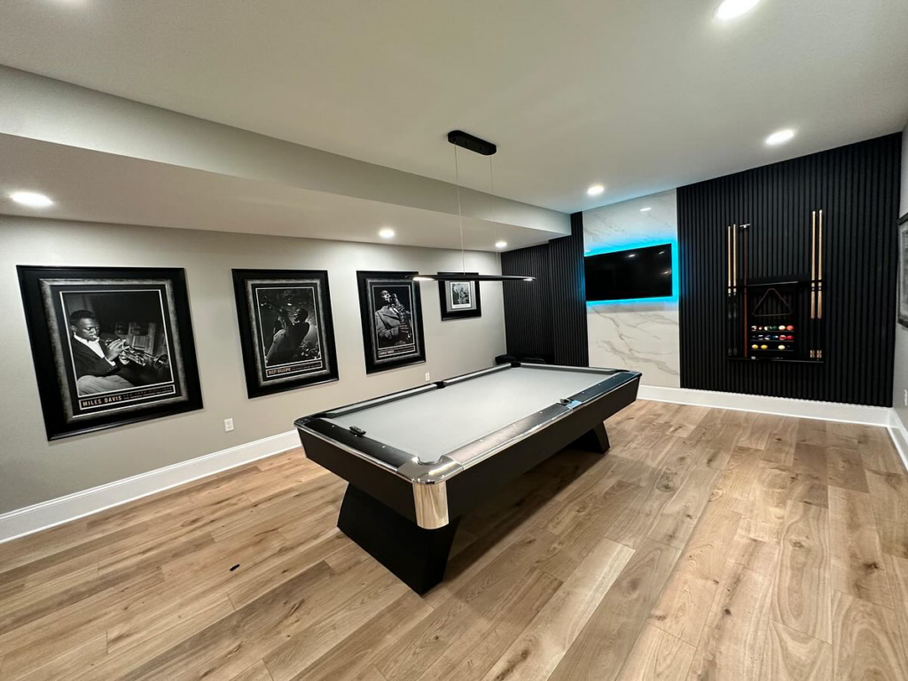 A beautifully finished basement with a pool table, modern wall paneling, and recessed lighting by Home Renovation & Design in Trumbull, CT.