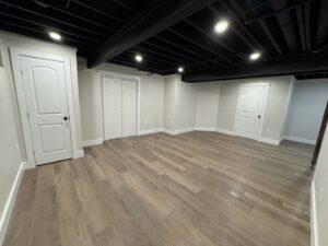 A finished basement room with new flooring, painted ceiling, and recessed lighting by Gateway Home Services KC LLC in Kansas City, MO.