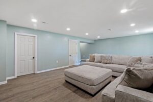 A newly finished basement living area with light blue walls and new flooring by Integrated Contracting and Renovations in Pittsburgh, PA.