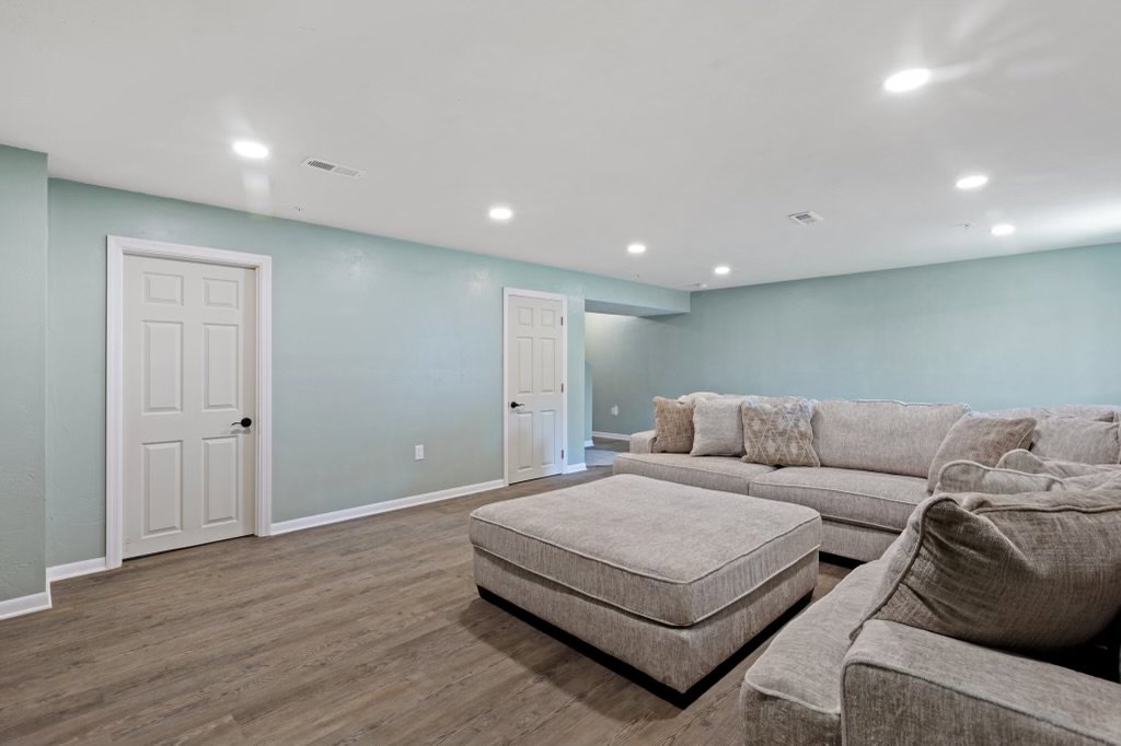 A newly finished basement living area with light blue walls and new flooring by Integrated Contracting and Renovations in Pittsburgh, PA.