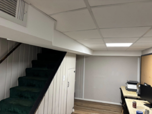 A completed basement renovation project with a new staircase, drop ceiling, and flooring by J Webb's Home Improvements LLC in Peoria, IL.