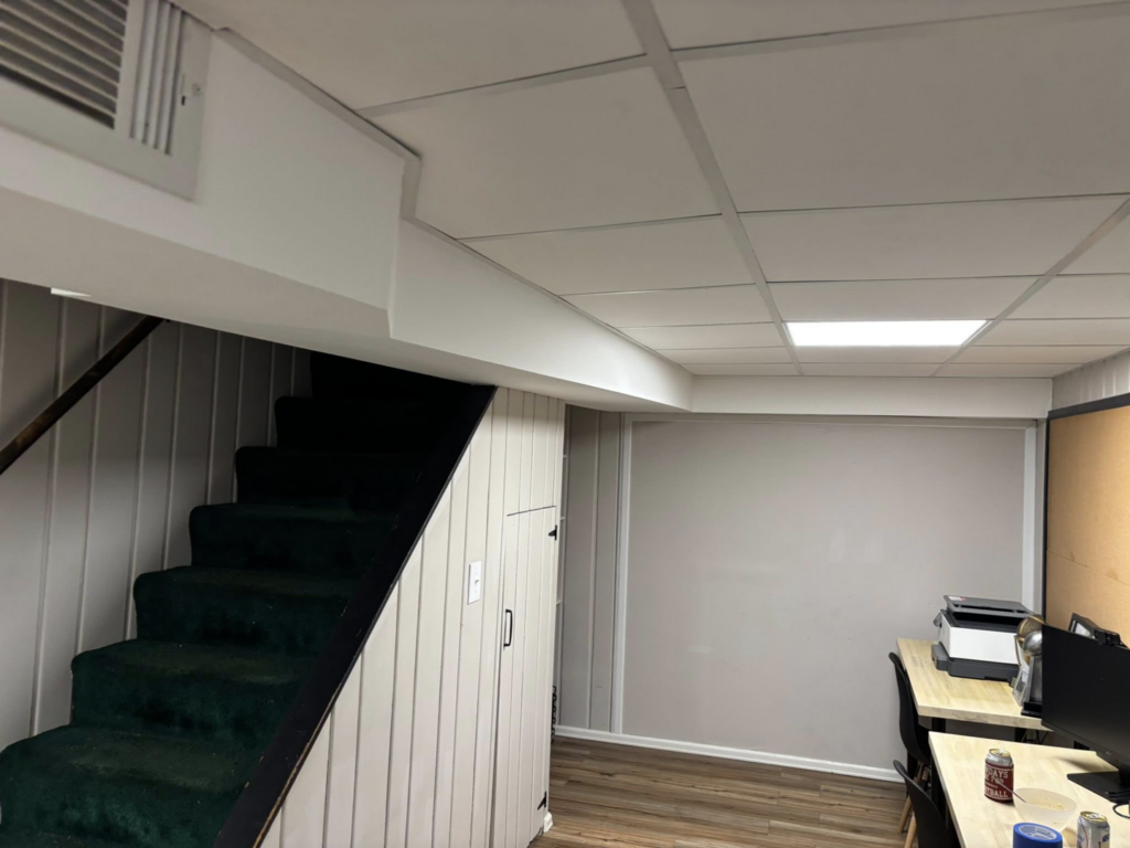 A completed basement renovation project with a new staircase, drop ceiling, and flooring by J Webb's Home Improvements LLC in Peoria, IL.