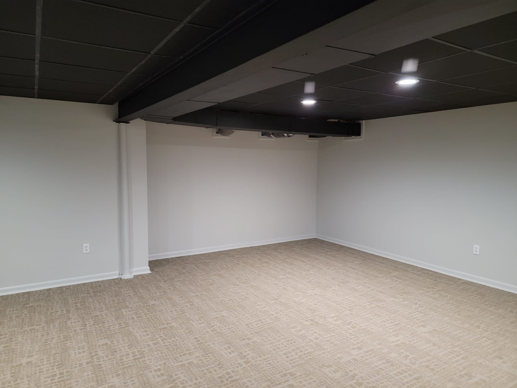 A newly finished basement room with a black drop ceiling and recessed lighting by Jake Fortin Carpentry Services in Pittsburgh, PA.