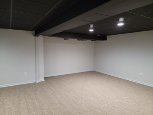 A newly finished basement room with a black drop ceiling and recessed lighting by Jake Fortin Carpentry Services in Pittsburgh, PA.