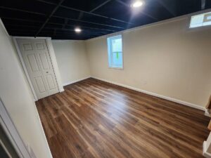 A newly finished basement room with laminate flooring and painted walls by APS Residential Services in Livonia, MI.