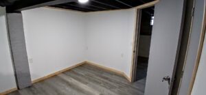 A newly finished basement room with new wood-look flooring and painted walls by Prime Construction And Flooring in Lorain, OH.