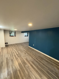 A finished basement room with new flooring, painted walls, and recessed lighting by Legacy Full Service Contracting LLC in Brackenridge, PA.
