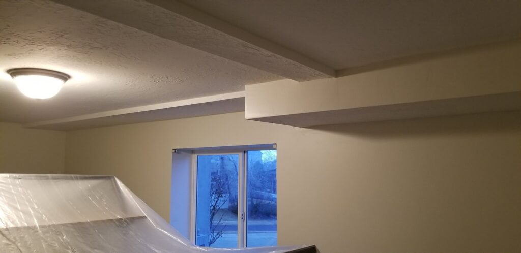 A finished basement room with painted walls and ceiling beams, showcasing work by Branham Handyman in Salt Lake City, UT