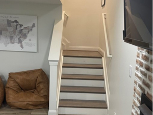 A newly finished basement staircase with wood treads and white railings by Smith Construction Services in Cincinnati, OH