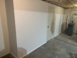 A newly finished basement wall with a door, painted white by Pinnacle Roofing & Construction LLC in Elkhart, IN.