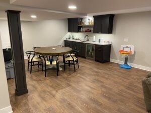 A finished basement featuring a wet bar, dining table, and open space, completed by Synergy Builders in West Chicago, IL.