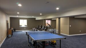 A spacious finished basement with new carpet, painted walls, and recessed lighting by QCON LLC in Aurora, CO.