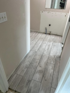A newly installed tiled floor in a bathroom, showcasing a completed project by Worths handyman services in Wasilla, AK.