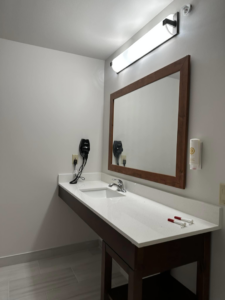 A newly installed bathroom vanity with a sink, mirror, and light fixture by Jay's Construction in Cincinnati, OH.