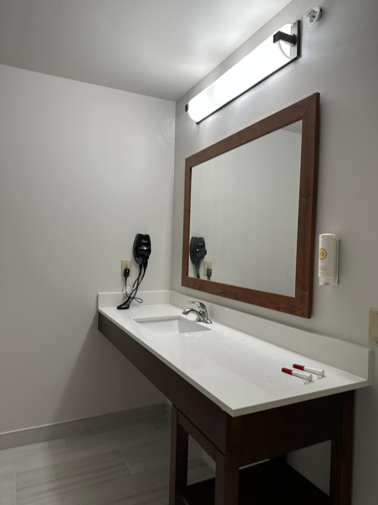 A newly installed bathroom vanity with a sink, mirror, and light fixture by Jay's Construction in Cincinnati, OH.