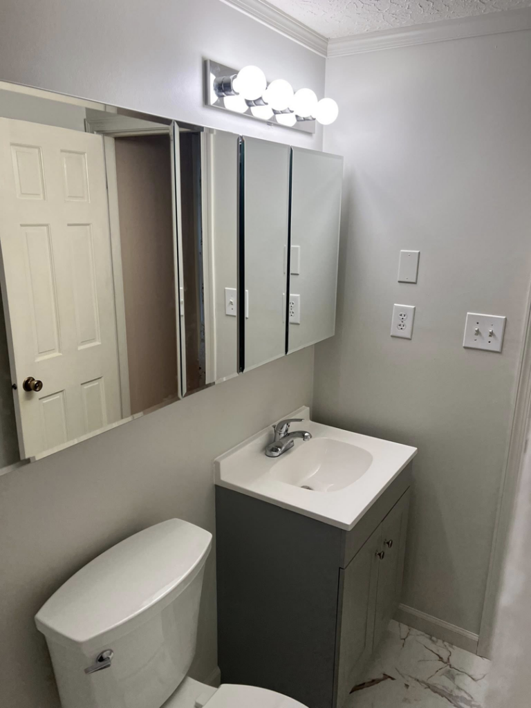 A finished bathroom with a new vanity, mirror, light fixture, and toilet by Home Changes in Knoxville, TN