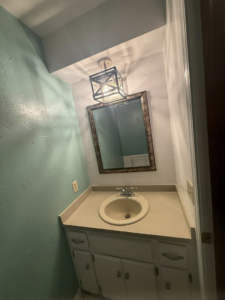 A newly painted bathroom with a vanity, sink, mirror, and light fixture by Duane Moss Painting in Oklahoma City, OK.