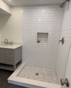 A finished bathroom featuring a new vanity, sink, and beautifully tiled shower, completed by Under The Wire Renovations in Atlanta, GA.