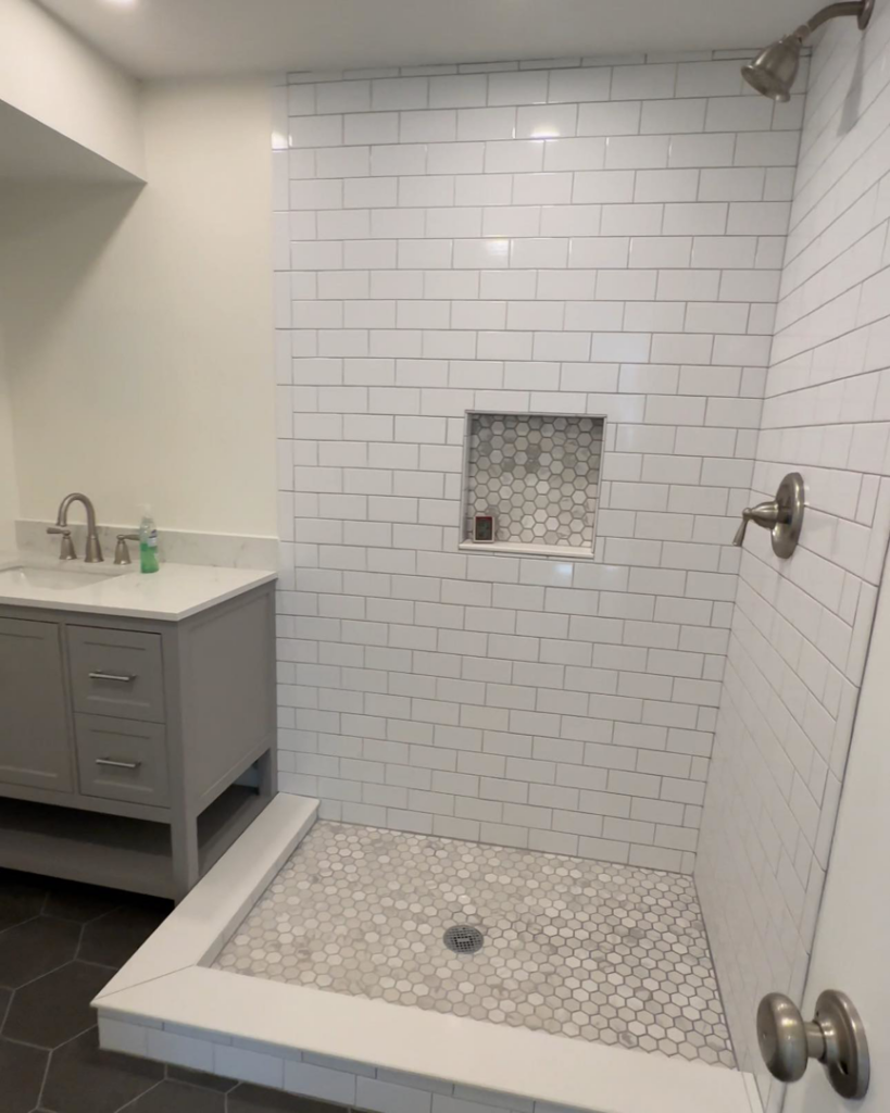 A finished bathroom featuring a new vanity, sink, and beautifully tiled shower, completed by Under The Wire Renovations in Atlanta, GA.