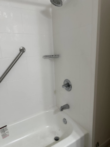 A newly installed bathtub and shower with white tiles and a grab bar by Jay's Construction in Cincinnati, OH.