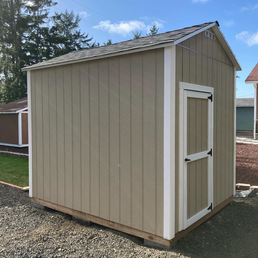 A finished beige shed with white trim and a matching door, built by Shed Crafters in Sycamore, IL