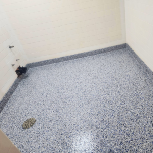 A finished blue-speckled epoxy floor with a floor drain, installed by Lifetime Epoxy Floors North Alabama in Boaz, AL.