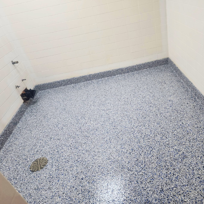 A finished blue-speckled epoxy floor with a floor drain, installed by Lifetime Epoxy Floors North Alabama in Boaz, AL.
