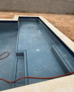 Newly finished blue speckled pool plastering with mosaic tiles by Prado & Sons Pool Plastering, Inc. in Glendale, AZ.