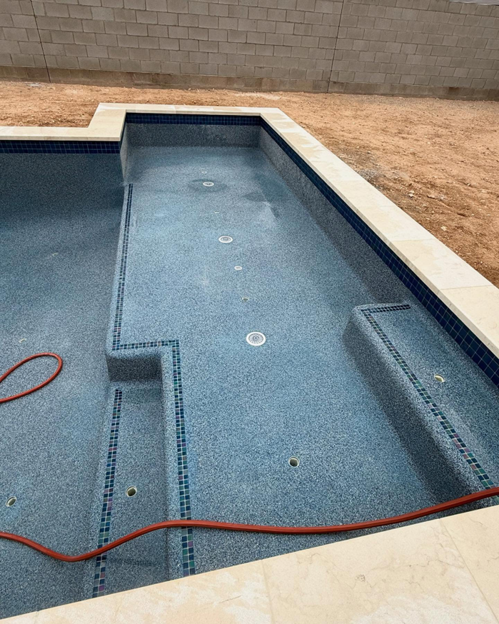 Newly finished blue speckled pool plastering with mosaic tiles by Prado & Sons Pool Plastering, Inc. in Glendale, AZ.