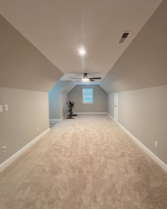 A spacious, newly finished bonus room with fresh carpet and a ceiling fan by Welcome Home Building Services in Winston-Salem, NC.