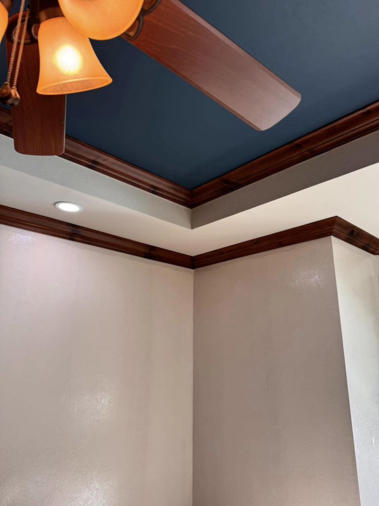 A beautifully finished ceiling with dark blue paint and new crown molding, completed by Sanders Construction & Handyman Services, LLC in Oklahoma City, OK.