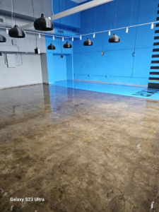 A large commercial room with a newly finished blue and concrete floor coating by Logical Drywall and Painting in St. Louis, MO.
