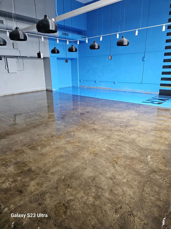 A large commercial room with a newly finished blue and concrete floor coating by Logical Drywall and Painting in St. Louis, MO.