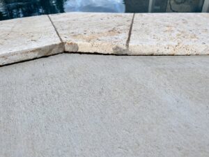 A close-up view of finished concrete next to stone pool coping by Allen's Concrete Finishing in Rock Hill, SC.