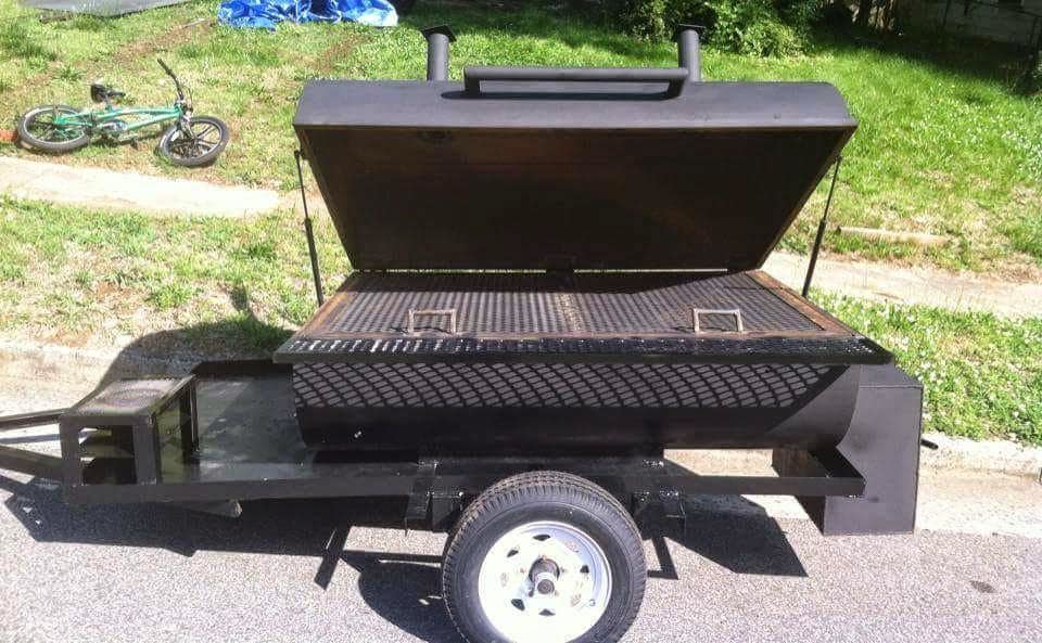 A finished custom-built black BBQ smoker on a trailer with the lid open, by Charlotte's Welding Service in Rock Hill, SC