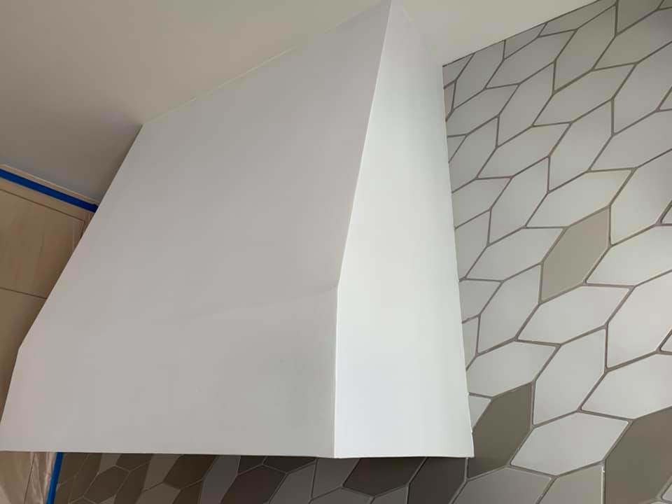 A close-up of a beautifully finished custom plaster range hood by Plasters of Italy in Plano, TX