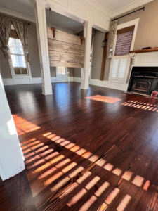 Finished dark hardwood floors in a living area with a fireplace by Trades by Taylor LLC in Huntsville, AL.