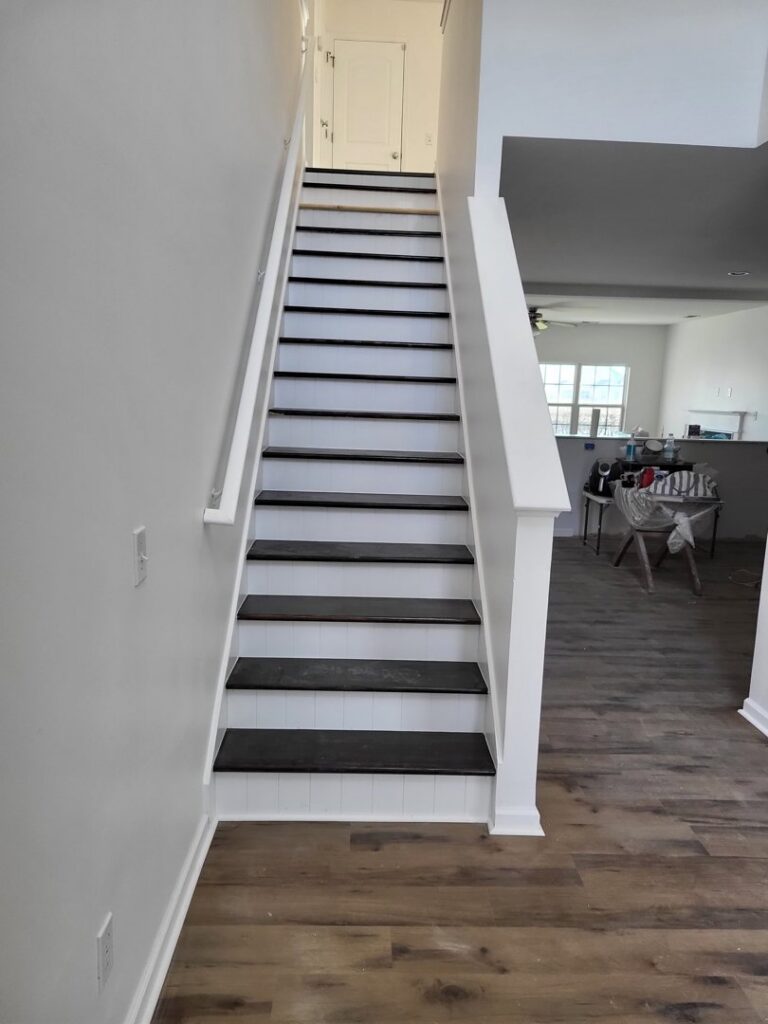 Finished stairs with dark treads and white risers installed by Gladiator Flooring LLC in Summerville, SC.