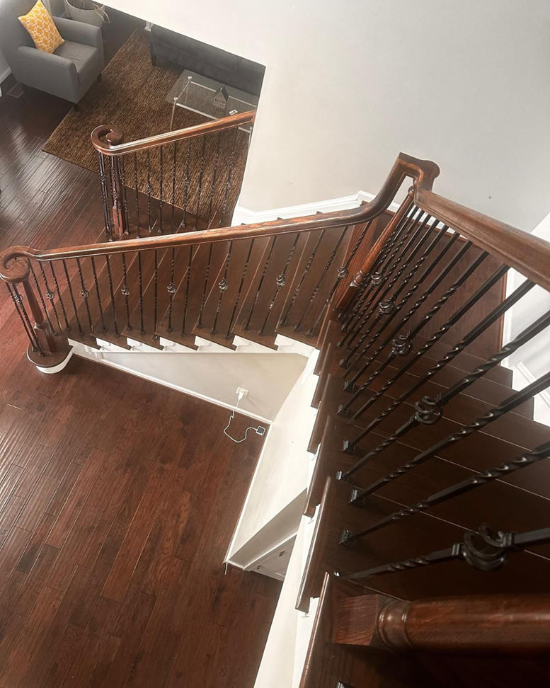 Finished dark wood staircase with elegant wrought iron balusters, viewed from above, by International Wood Floors in Gaithersburg, MD