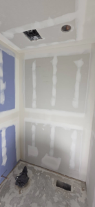 Finished drywall in a room corner with ceiling cutouts and floor drain by AJ's Drywall & Finishing, LLC in St. Louis, MO.