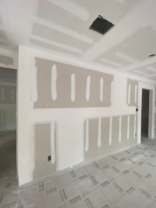 A close-up of a finished wall with newly installed and taped drywall and electrical outlets, completed by TechPro Constructions in Houston, TX.