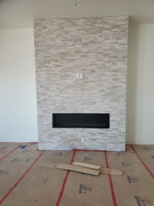 A newly finished fireplace with decorative stone veneer and an electric insert by AV Handyman Services in Rio Rancho, NM.