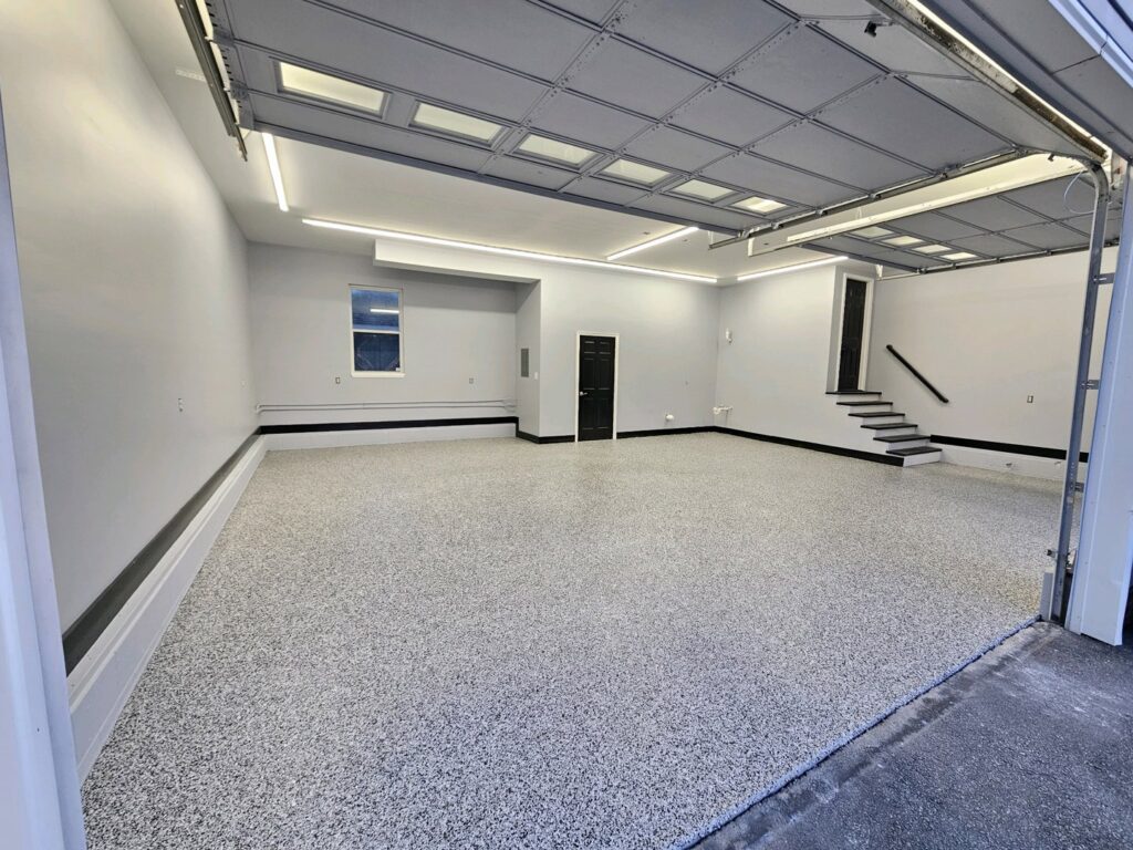 A spacious, newly finished garage with an epoxy floor and freshly painted walls, a handyman service by Randy Overacre Painting Company in Virginia Beach, VA.