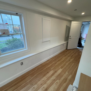 A newly finished hallway with new flooring, white walls, and window trim by Markos Construction in Cambridge, MA.